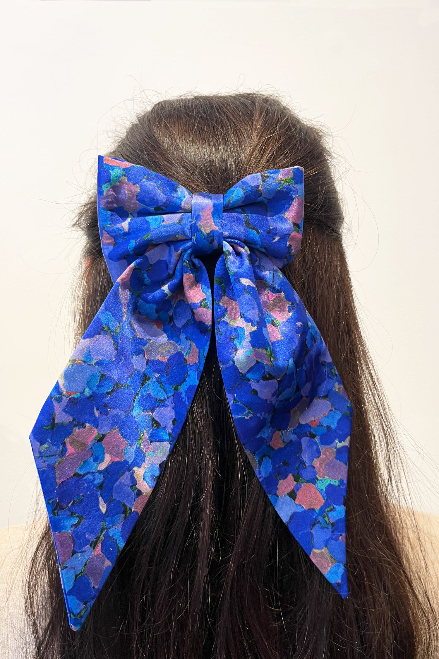 Model wearing blue printed silk satin bow with ribbon styling and silver hair clip.