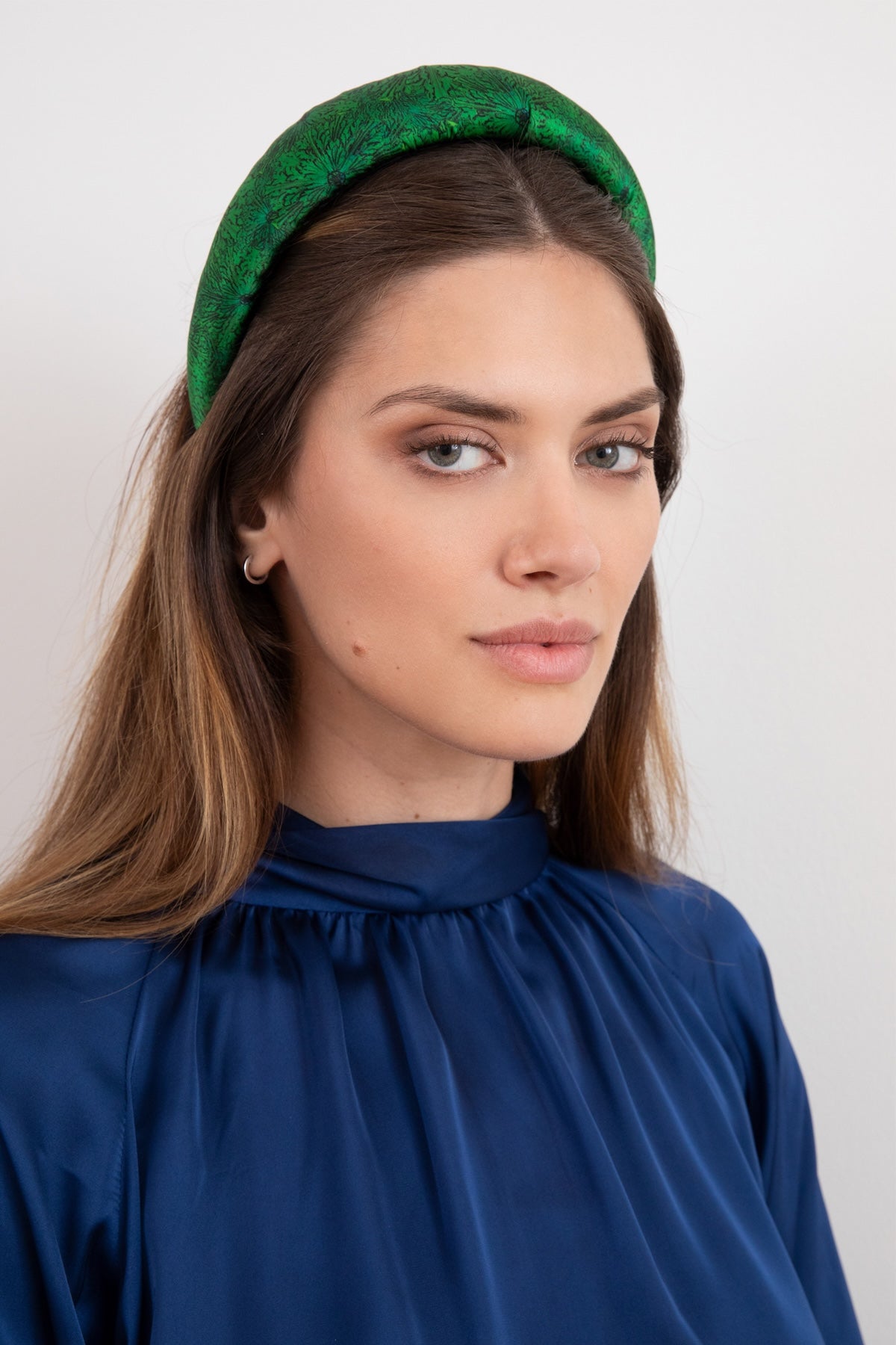 A beautiful emerald green silk printed padded headband worn by a model that is luxurious and stylish
