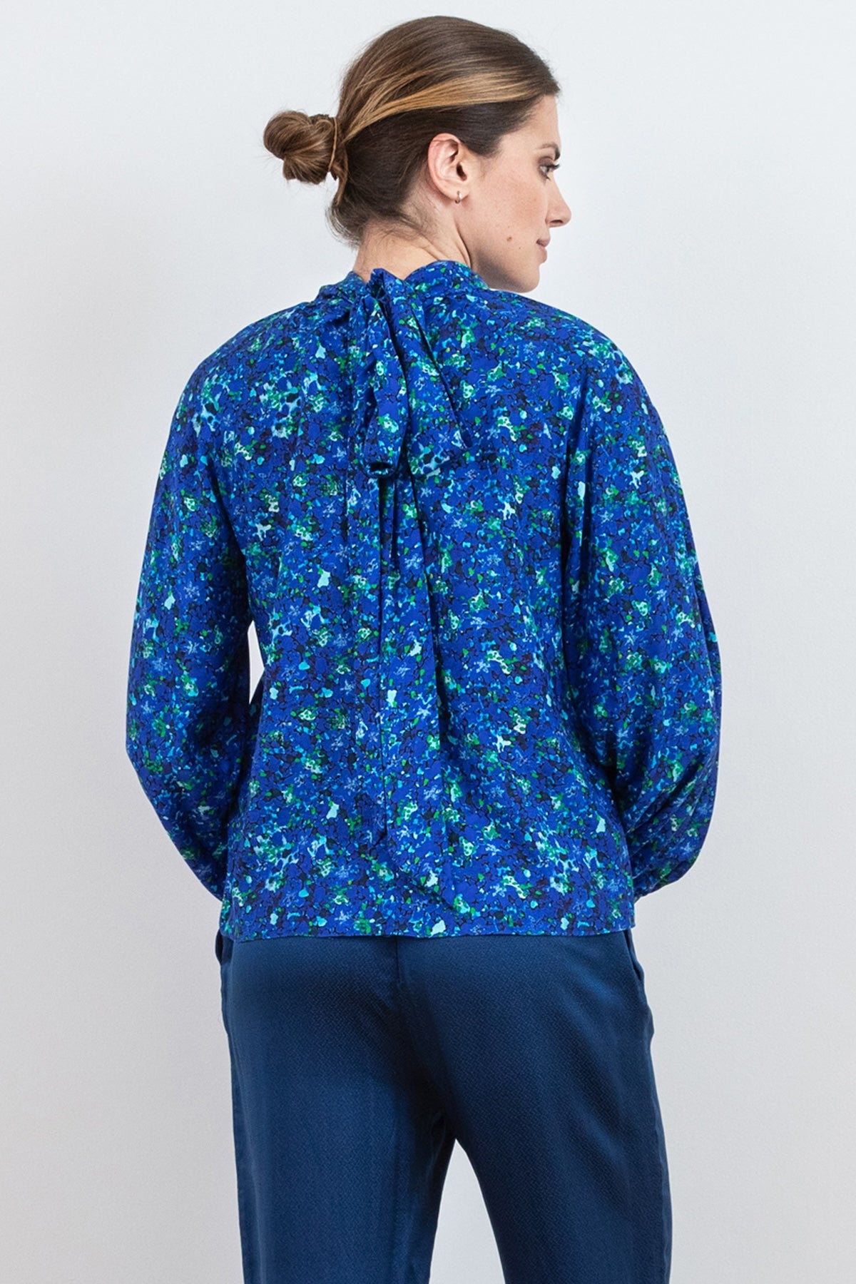 Back view of halter neck silk bamboo top with long raglan sleeves with tie collar in blue floral print.