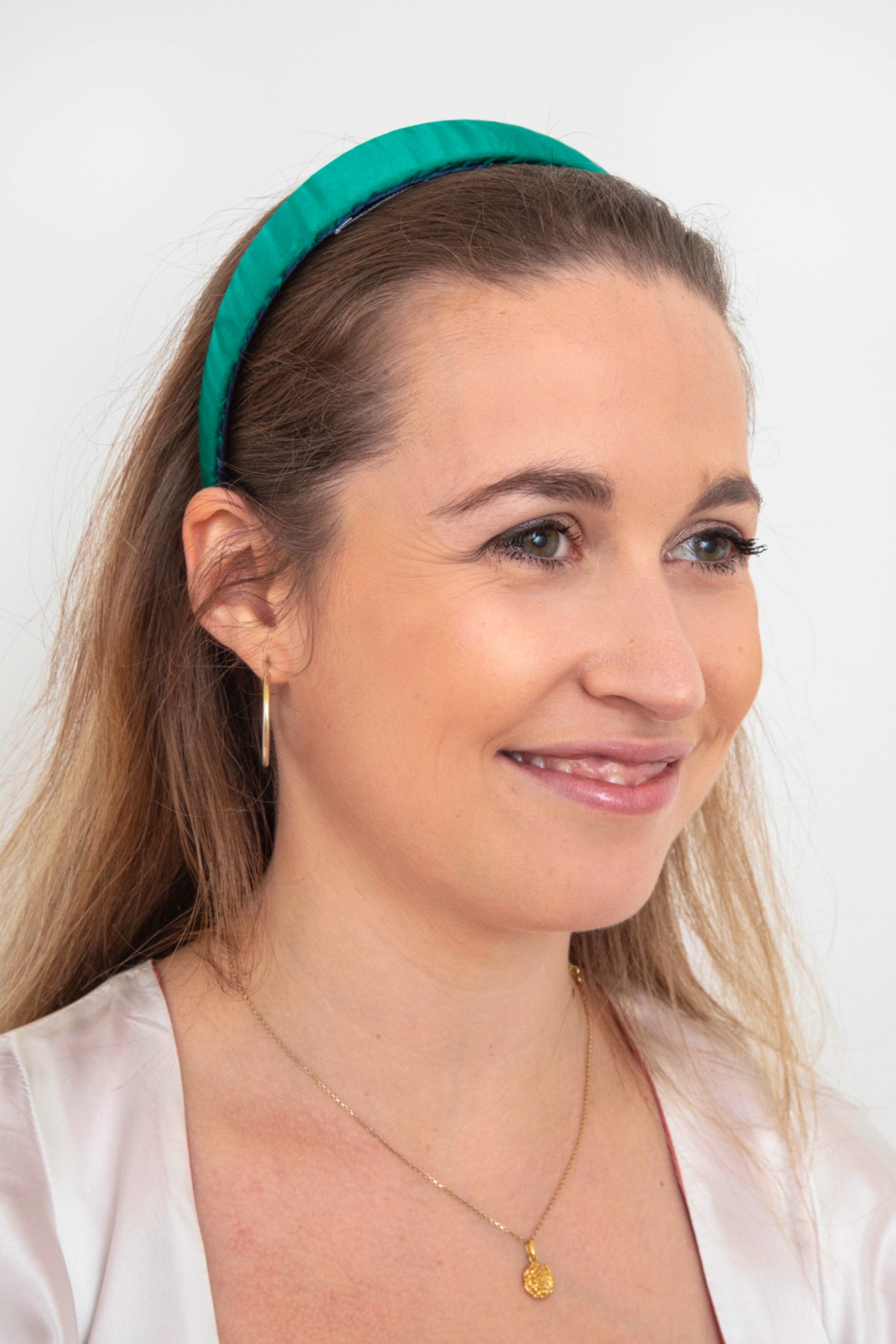 A vibrant plain emerald silk satin headband worn by a model that is perfect for day or evening wear