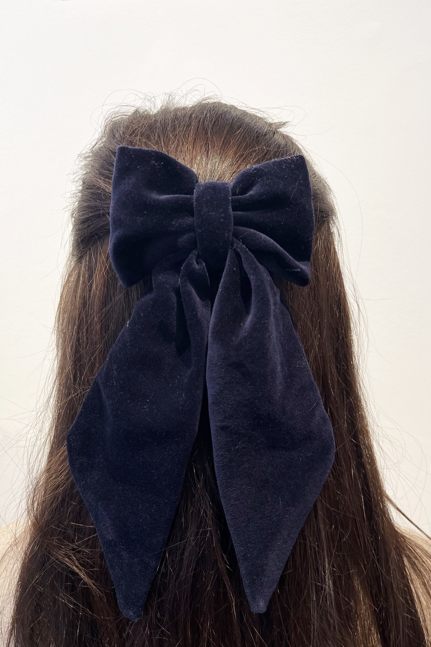 Model wearing navy velvet bow with ribbon styling and silver hair clip.