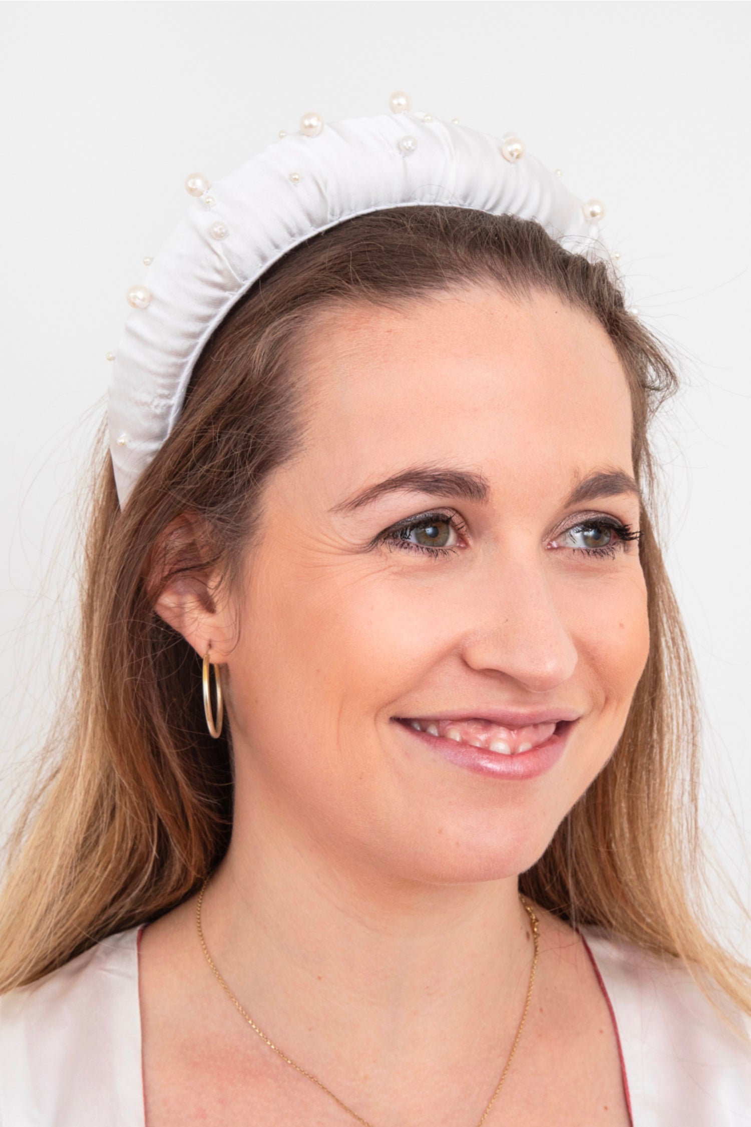 a glamorous white silk padded headband with beautiful pearl detail spread out over the headband worn by a model elegantly