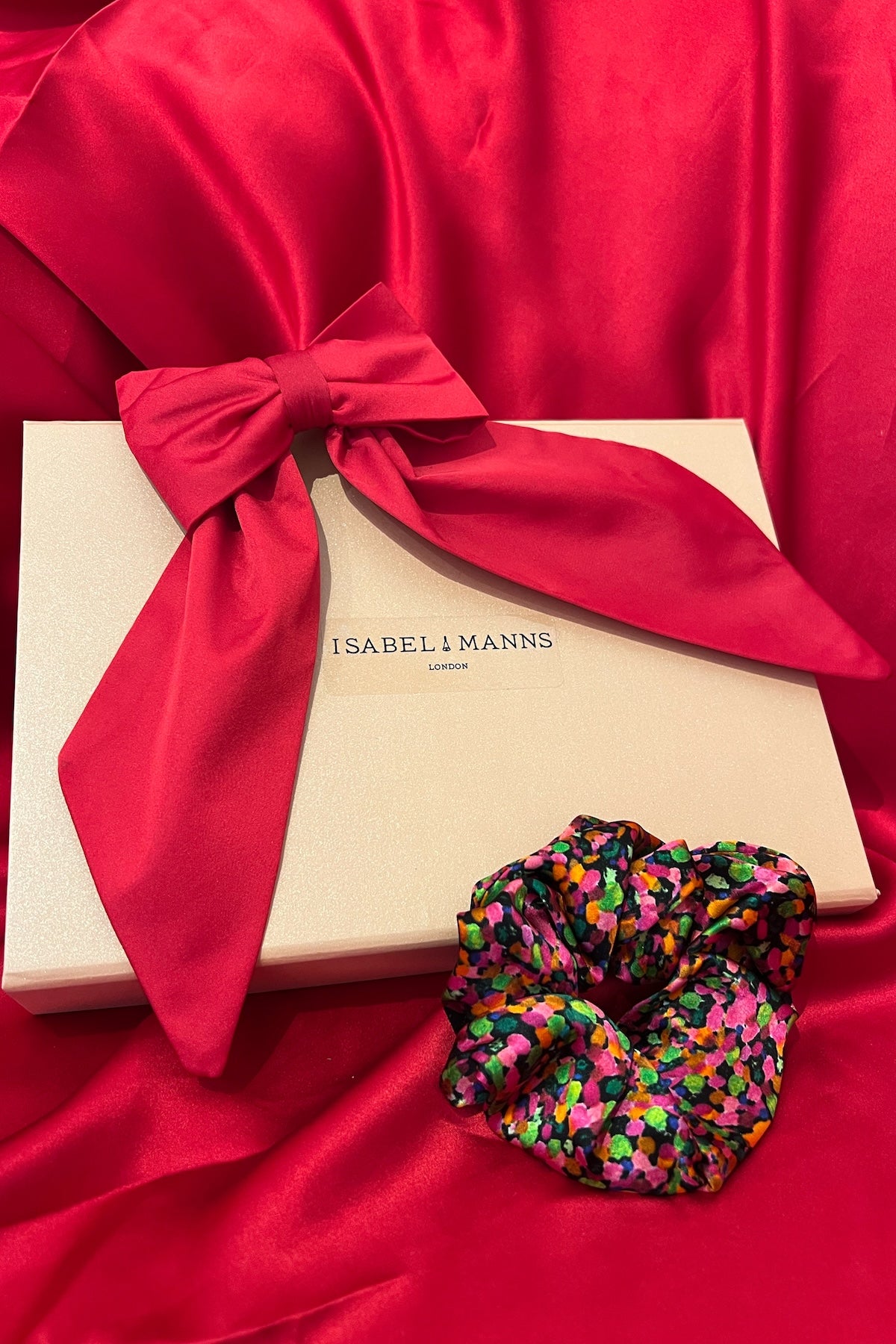 a gift box featuring a pink bow and printed silk scrunchie