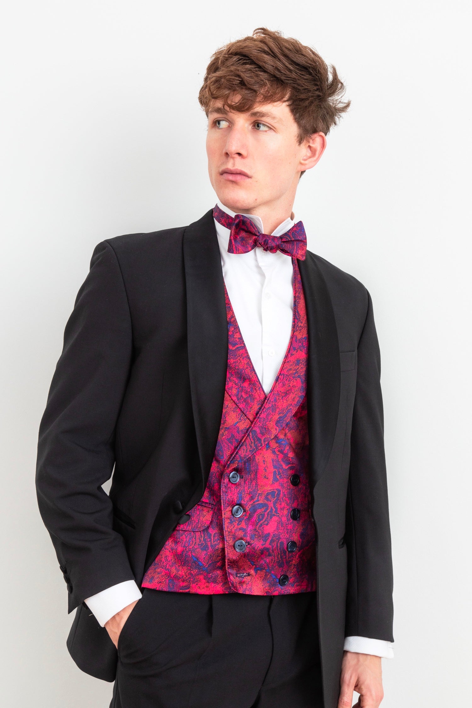 a mens silk waistcoat in a stylish and colourful design that is worn by a gentleman with a matching bow tie in black tie