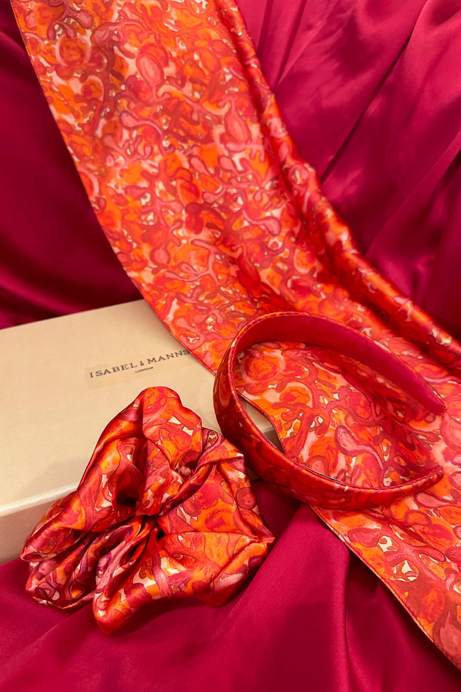 Long double-sided silk satin scarf in red and pink swirling print, with matching headband and scrunchie, and large pink gift box bow tied ribbon.