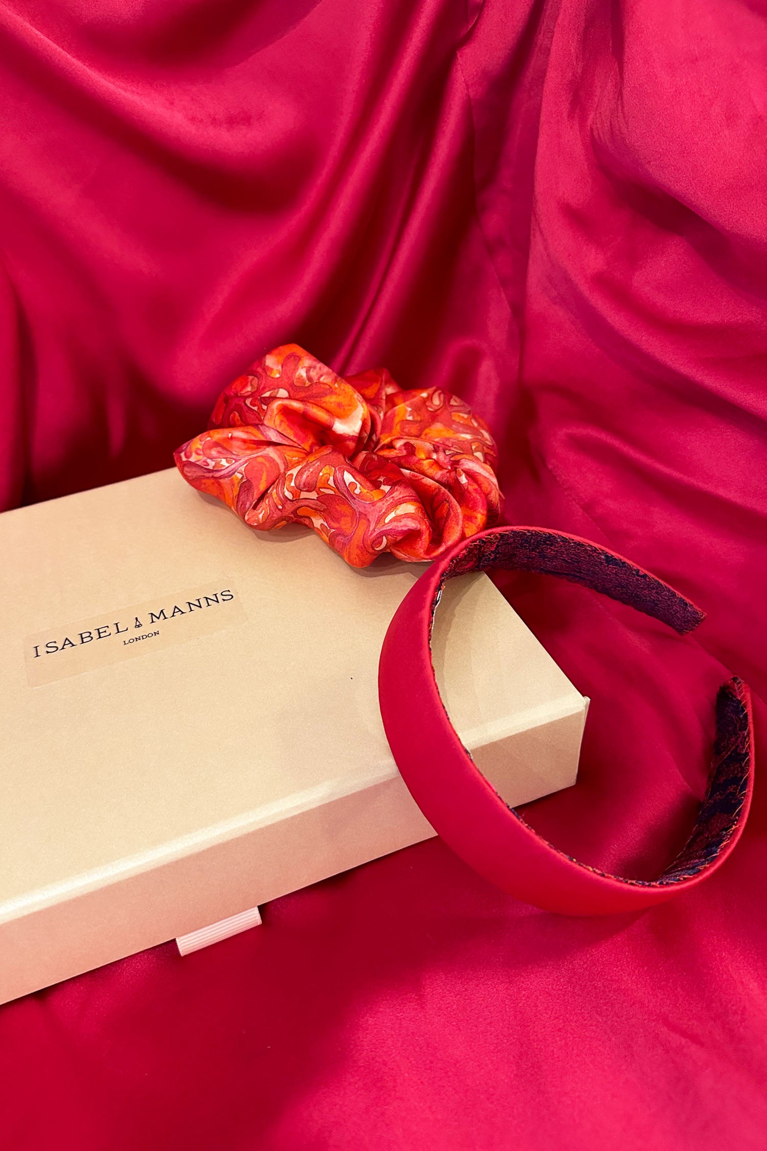 Raspberry pink headband with red and pink swirling print scrunchie and medium pink gift box bow tied ribbon.
