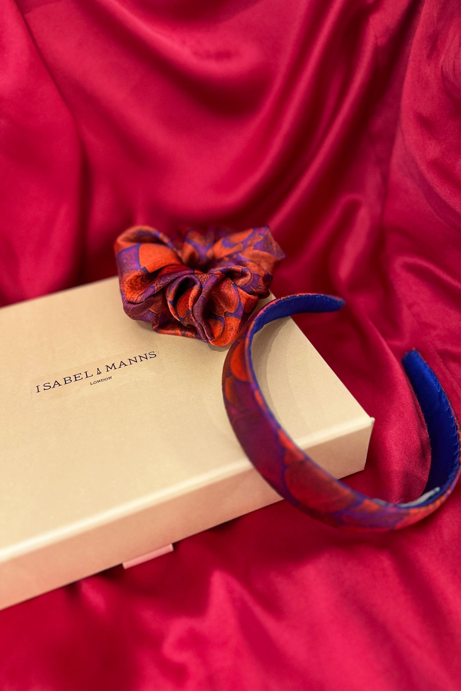 Red pebble print silk satin headband with matching scrunchie and medium pink gift box bow tied ribbon.