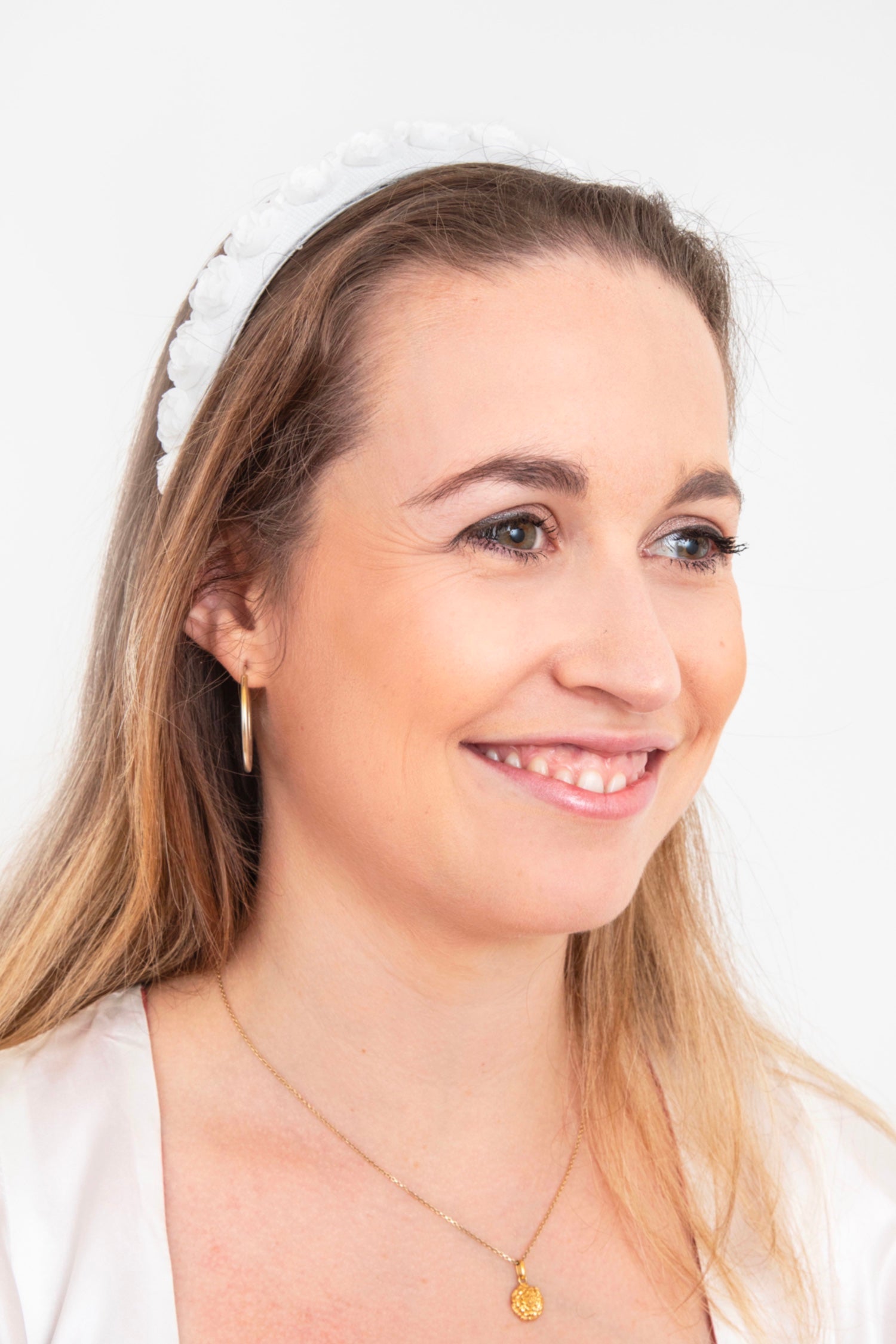 a pretty white headband with delicate rose detail that is ideal for a bride worn beautifully by a model