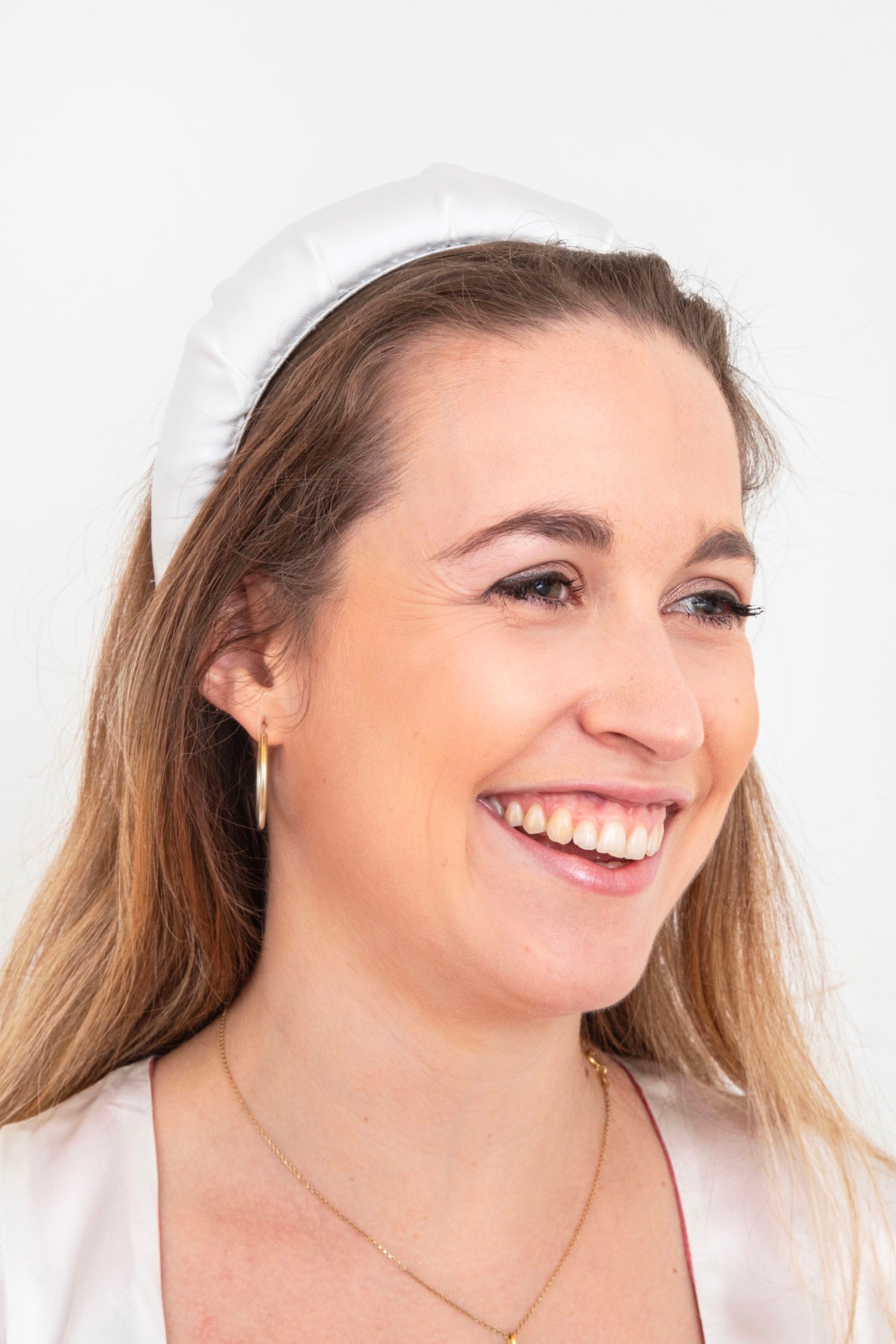 white padded headband worn by a happy model which is ideal for your wedding day to add a little detail