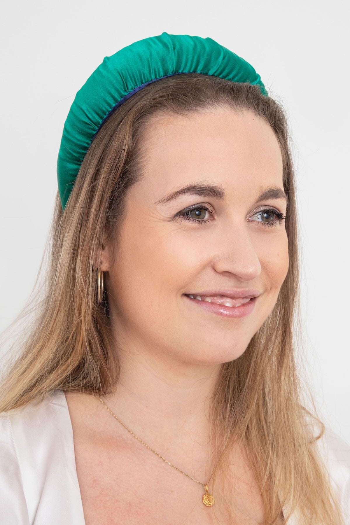 A unique and vibrant emerald green plain silk satin padded headband worn by a model that is stylish and timeless