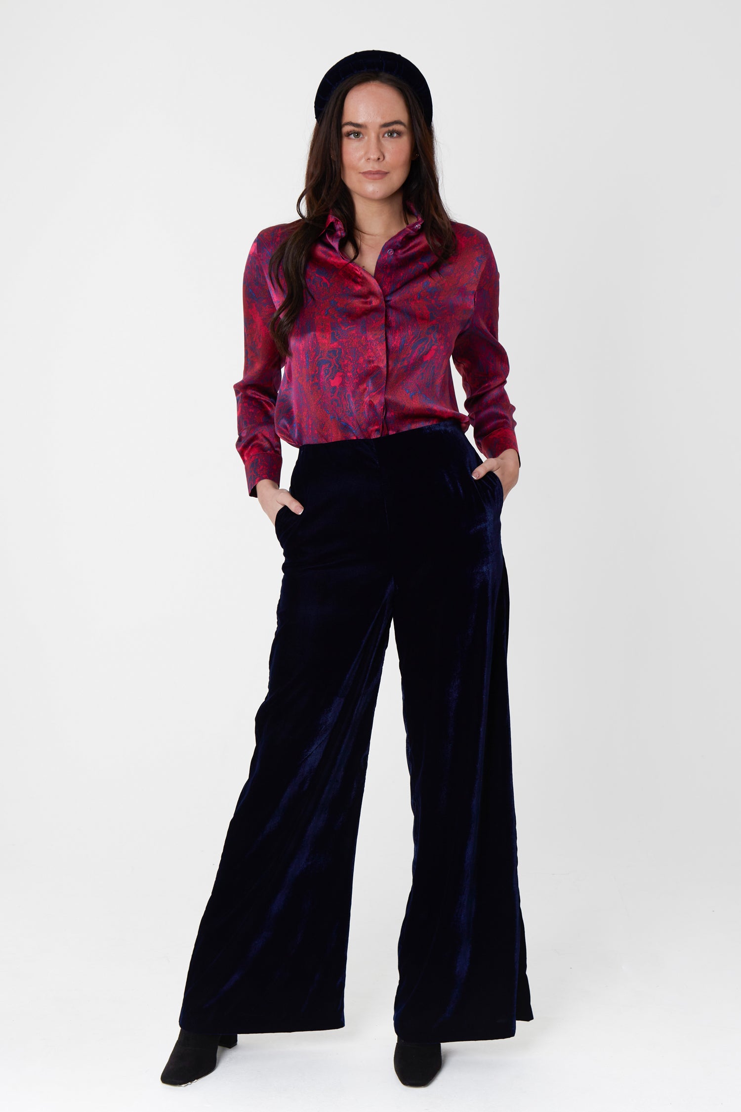 Model wearing high waisted palazzo pants in navy velvet, worn with matching padded headband and Lisa Shirt in red marble print.