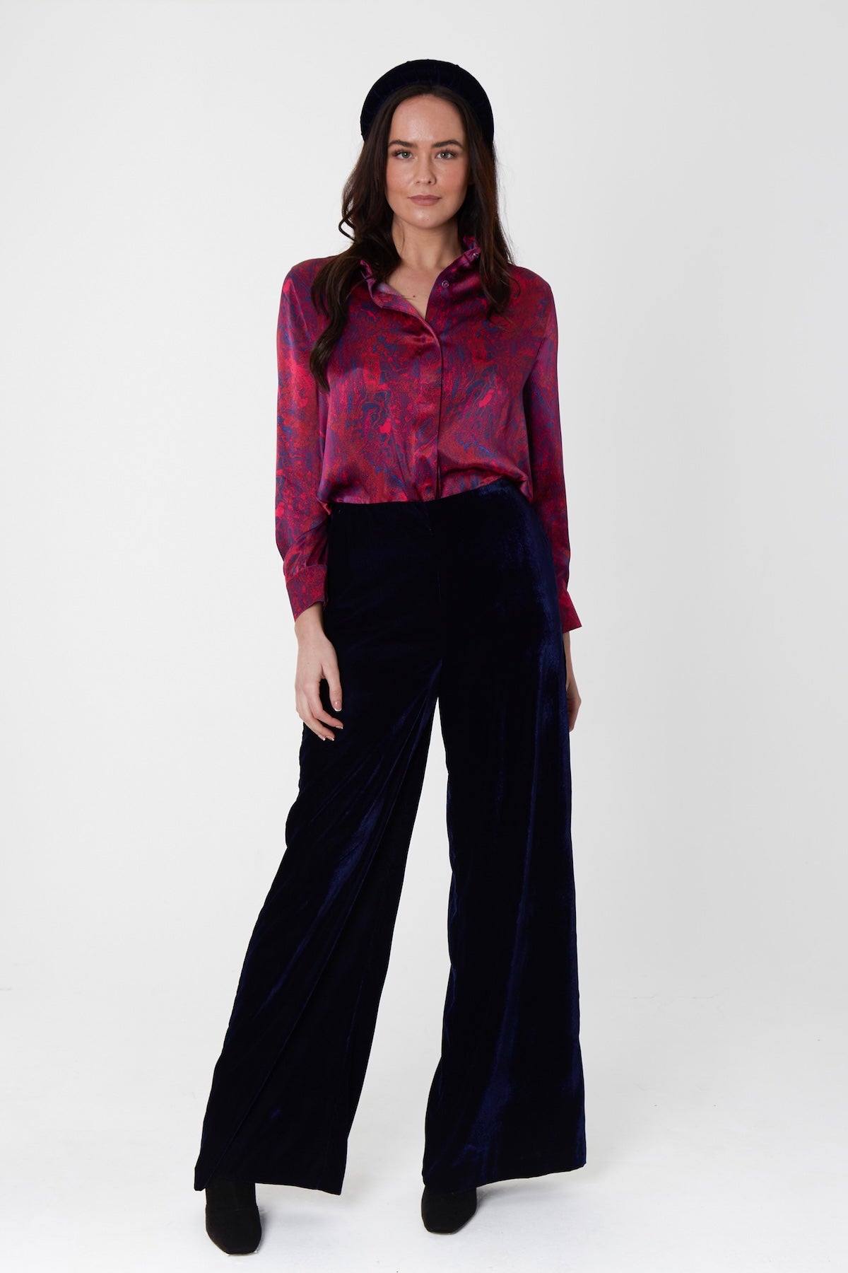 A burgundy marble inspired printed silk satin shirt worn by a model with navy palazzo pants and velvet padded headband showing how to wear effortlessly