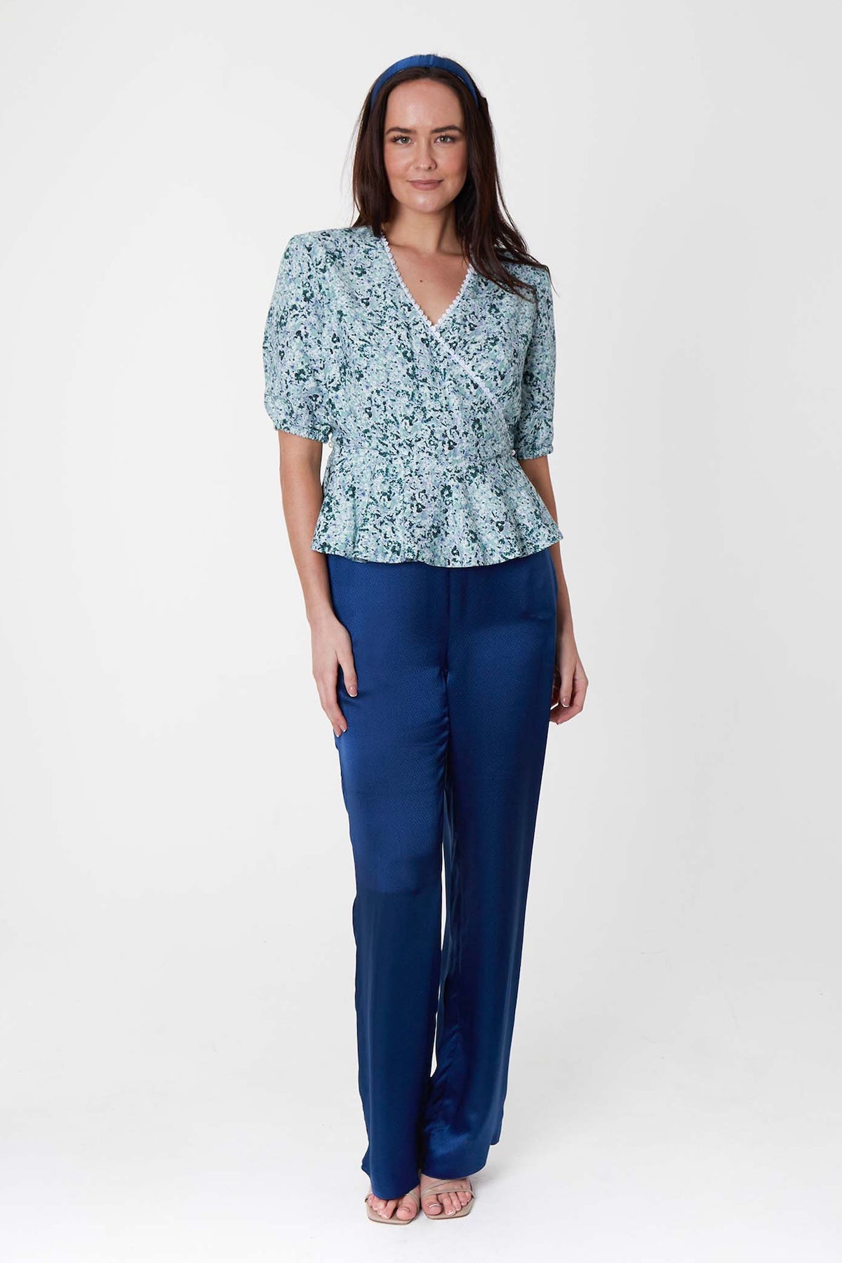 Model wearing high waisted narrow fit silk viscosepalazzo pants in textured navy, worn with pale green floral wrap Judy Top and matching headband.