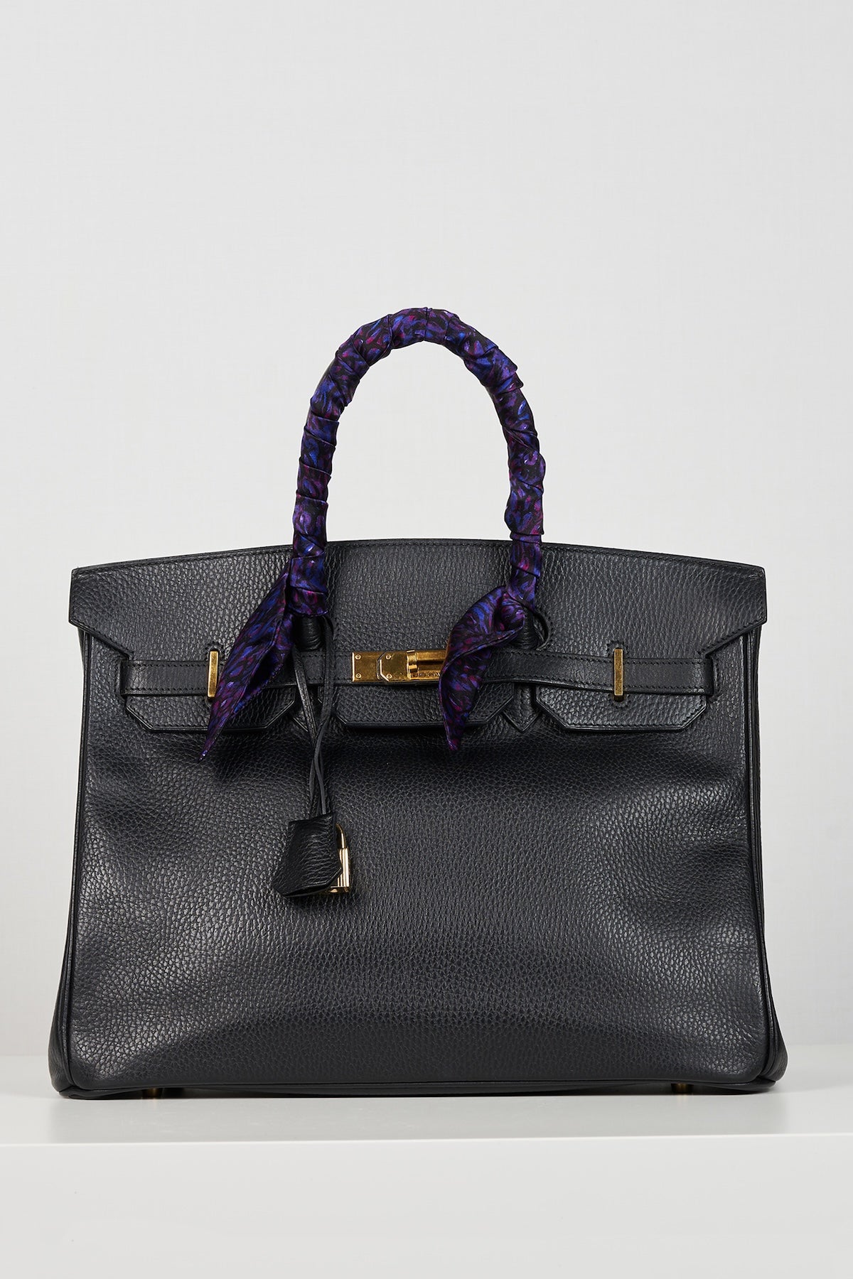 a purple printed scarf tied on a handle of a bag