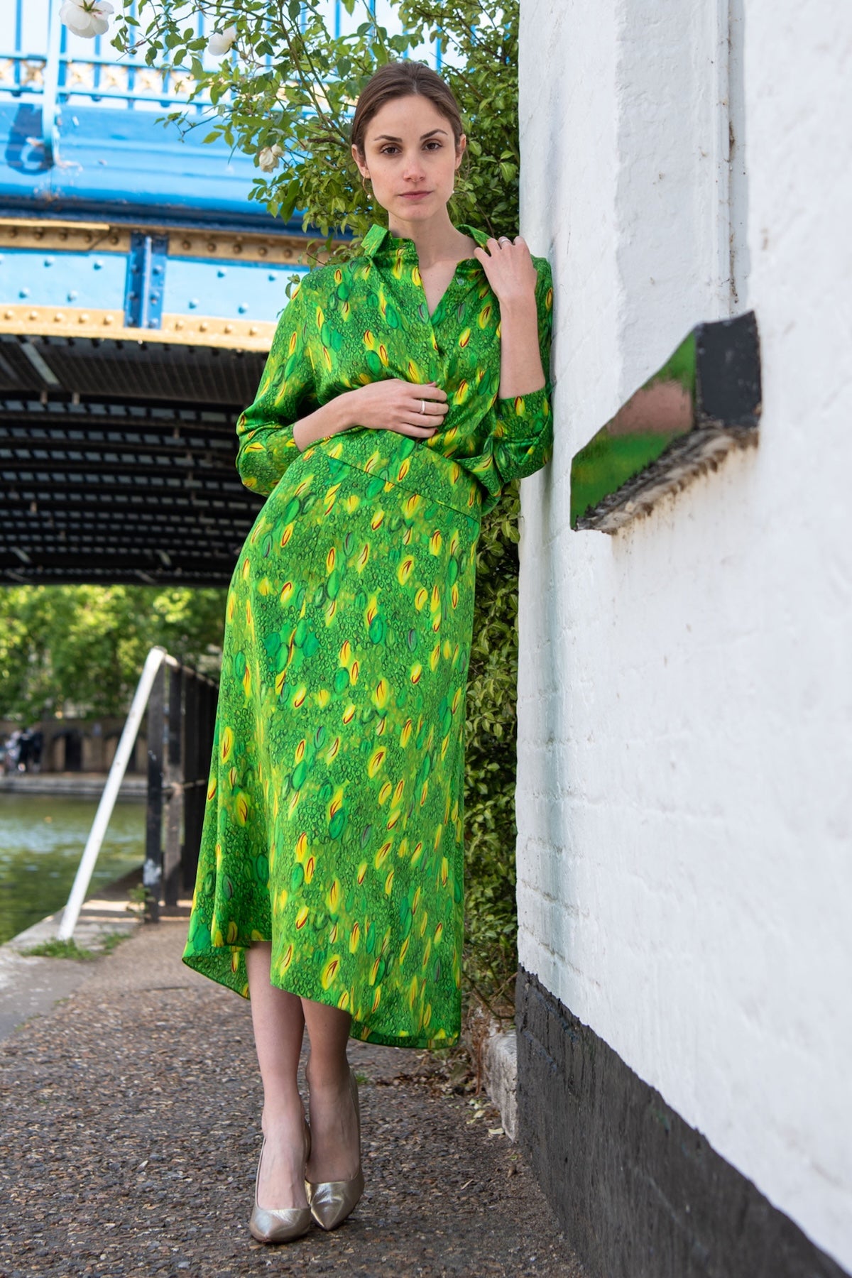 Model wearing a colourful green and yellow silk printed Isabel Manns narrow a-line midi skirt with wide waistband, worn with matching Lisa Shirt.