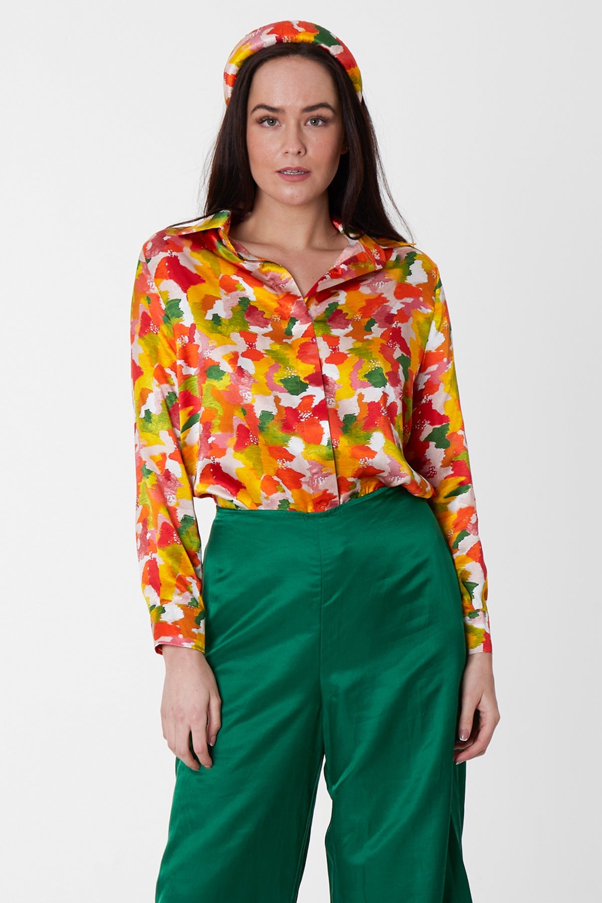 a colourful silk printed shirt showing colours of orange, red, pink, green and yellow worn with a matching headband and green trousers showcased by a model