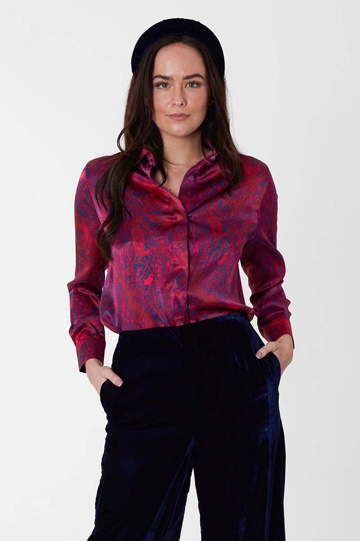 A burgundy marble inspired printed silk satin shirt worn by a model with navy palazzo pants and velvet padded headband