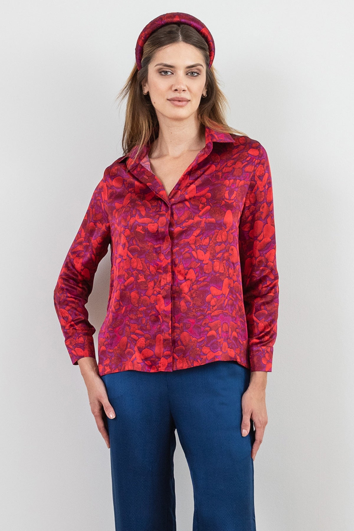 a red pebble inspired printed silk satin shirt worn effortlessly by a model with a matching padded headband and navy trousers