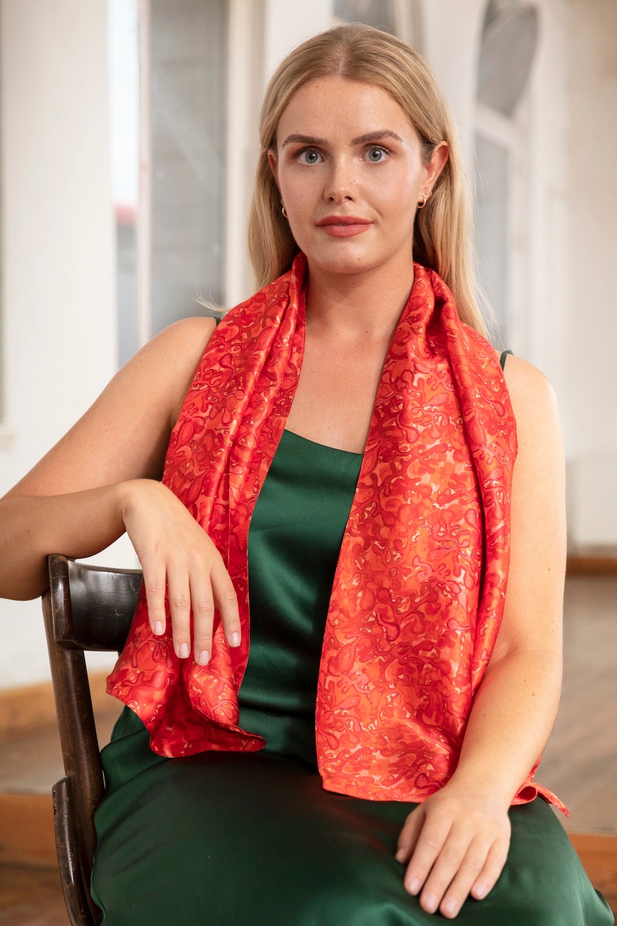 Model wearing long double-sided silk satin scarf in vivid red and pink print, with forest green Alice Dress.