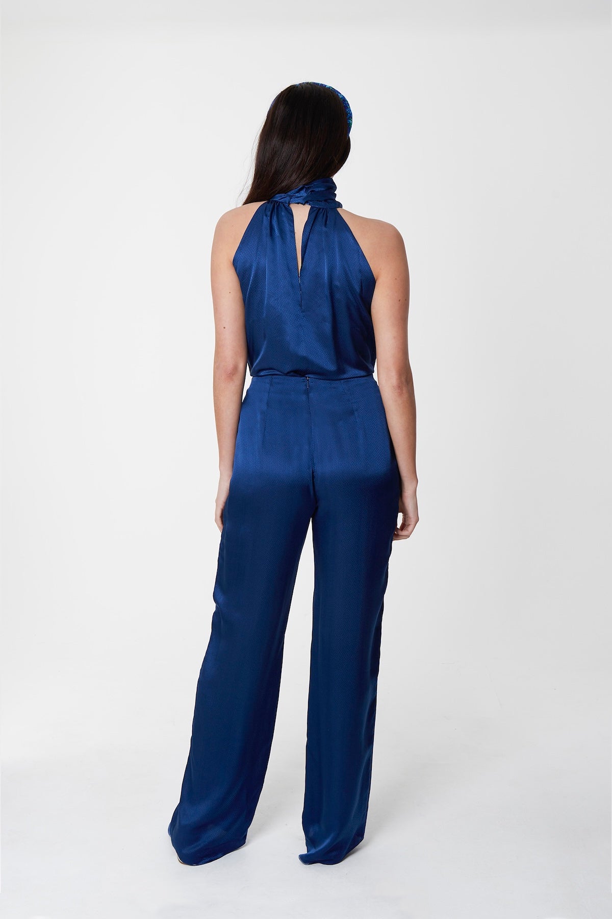 A back view of reversible halter neck silk satin top with tie collar in navy with matching navy Georgia trousers.
