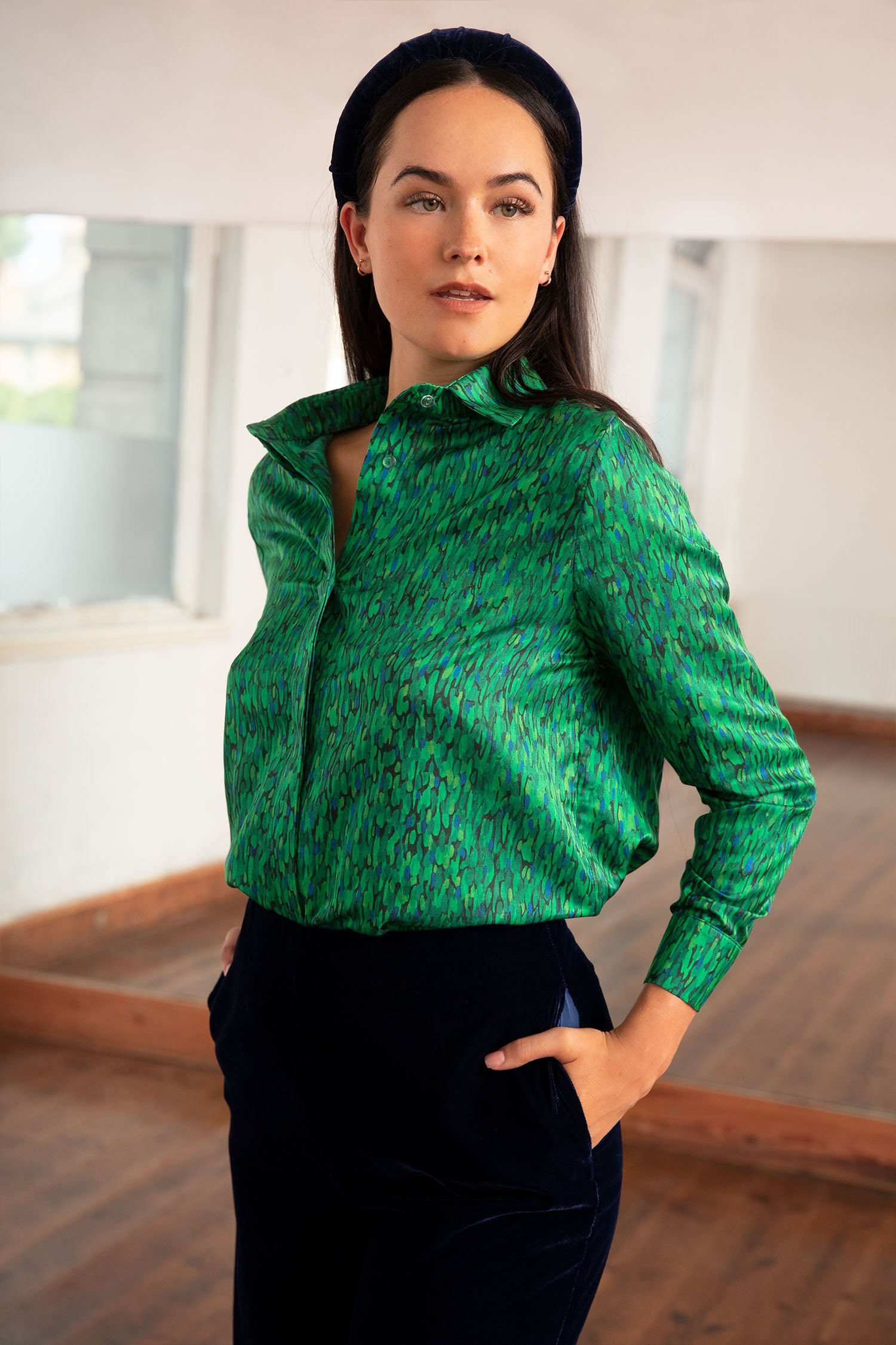 a green printed silk cotton shirt worn by a model with navy velvet trousers and matching headband that is all made in London