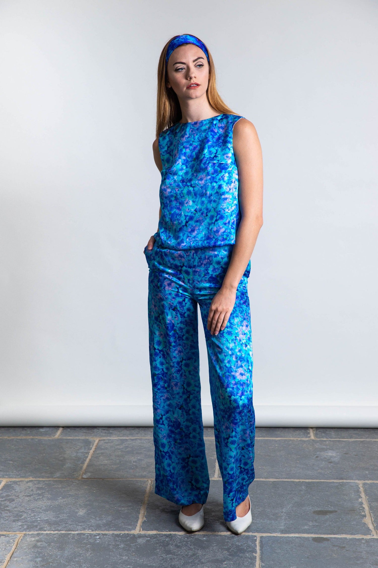 Model wearing Isabel Manns high waisted palazzo pants in silk satin turquoise print, worn with matching Kelly top and headband.