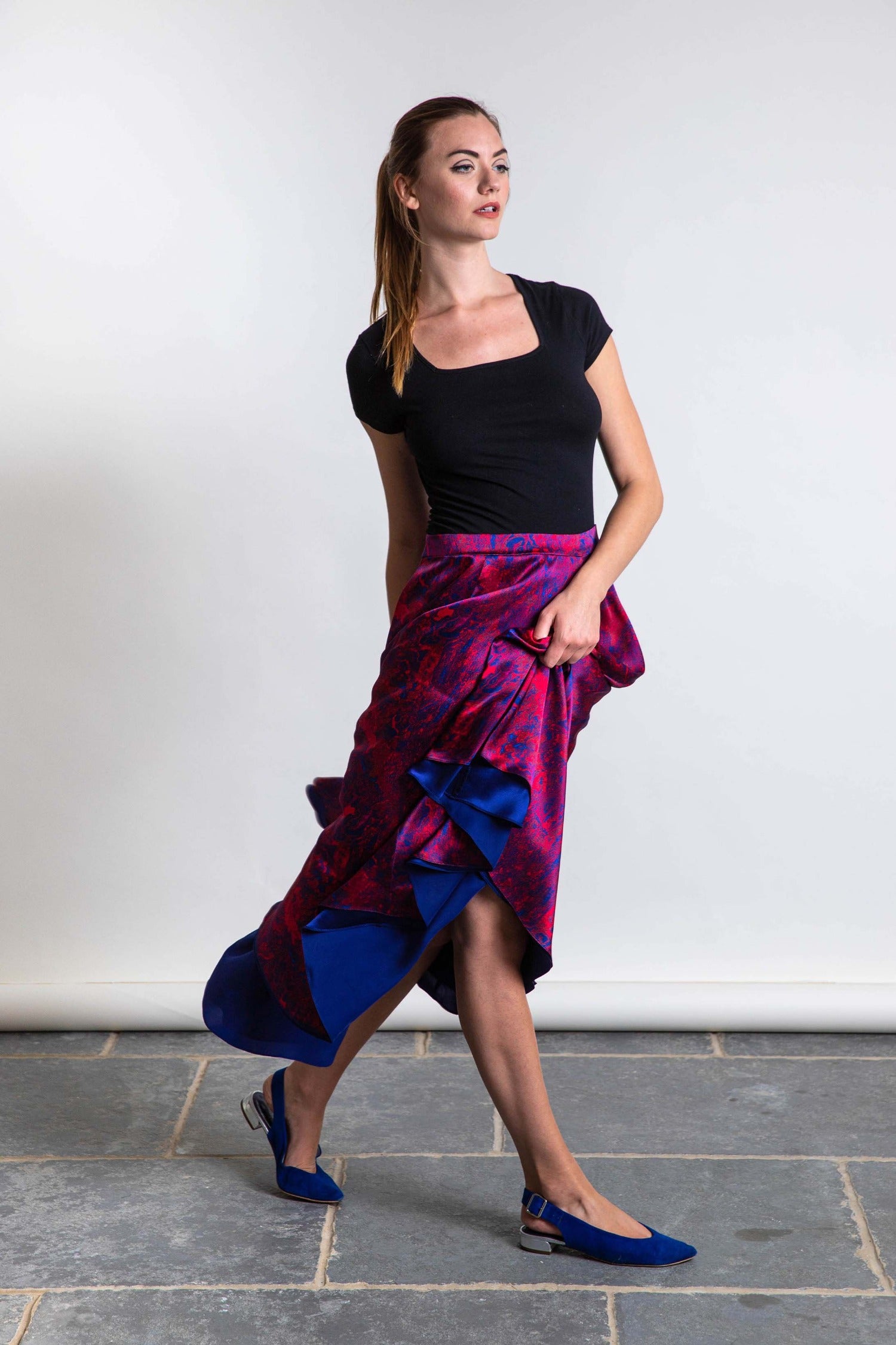 Model wearing reversible voluminous a-line midi silk satin red marble print skirt, worn with black t-shirt.