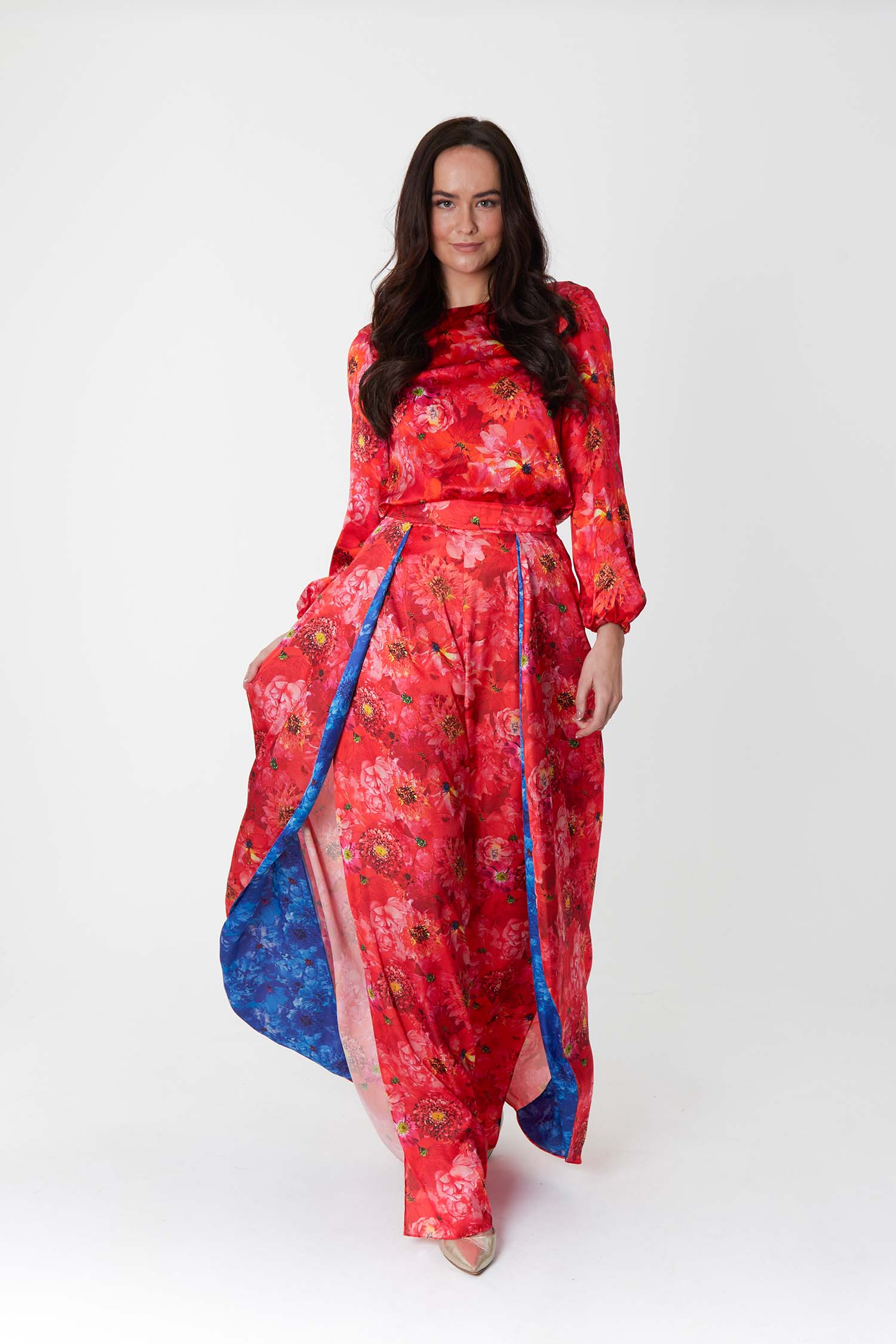 Model wearing an Isabel Manns wide leg wrap around style silk satin trousers in vibrant floral coral print and vibrant floral blue print, worn with matching long sleeve Clementine top.