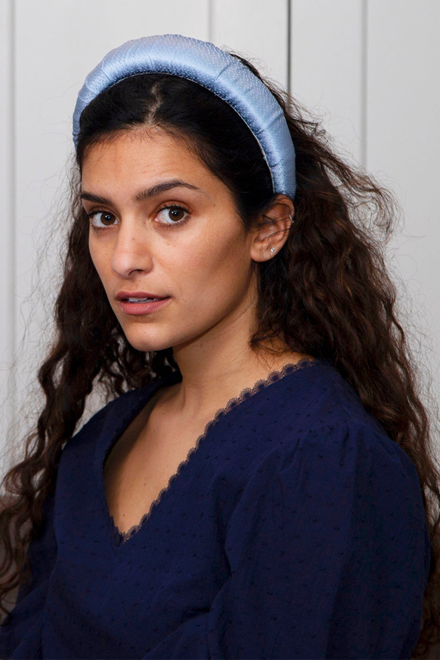 A soft and subtle pale blue silk padded headband worn elegantly by a model