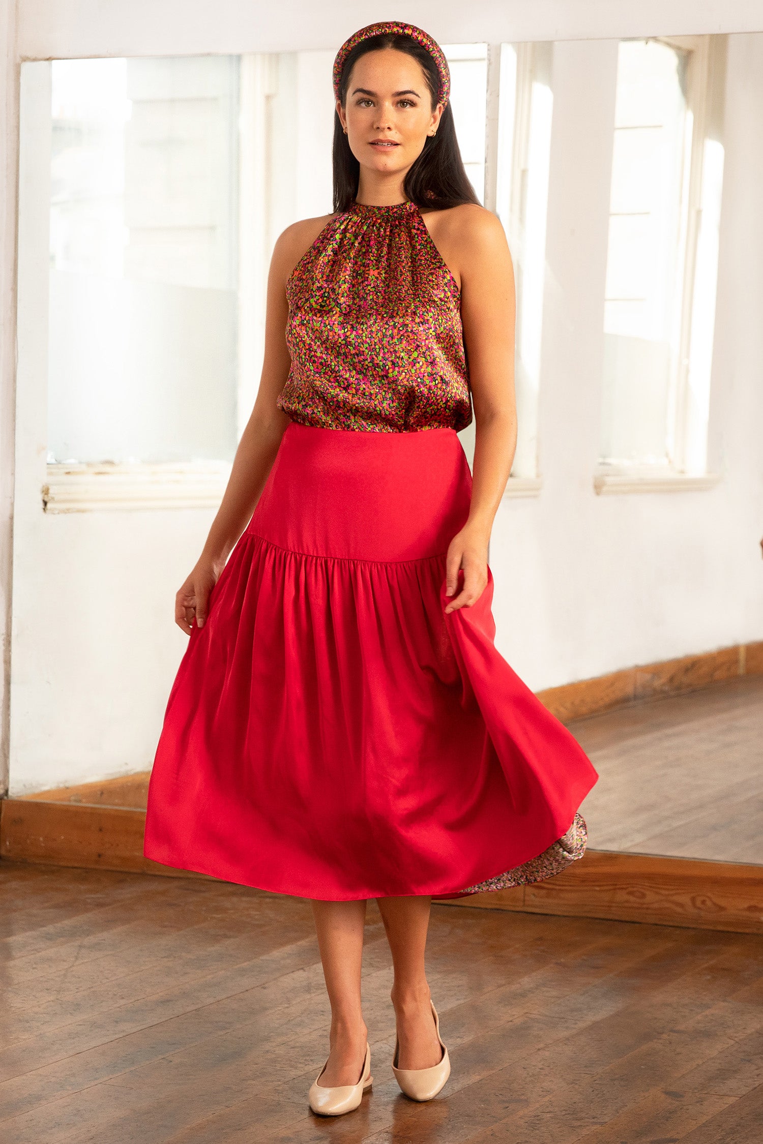 Model wearing reversible a-line midi silk satin skirt with an extra wide waistband and gathered detail from hips down in Raspberry Pink, worn with halter neck Annie Top in Neon Light and Raspberry Pink headband.