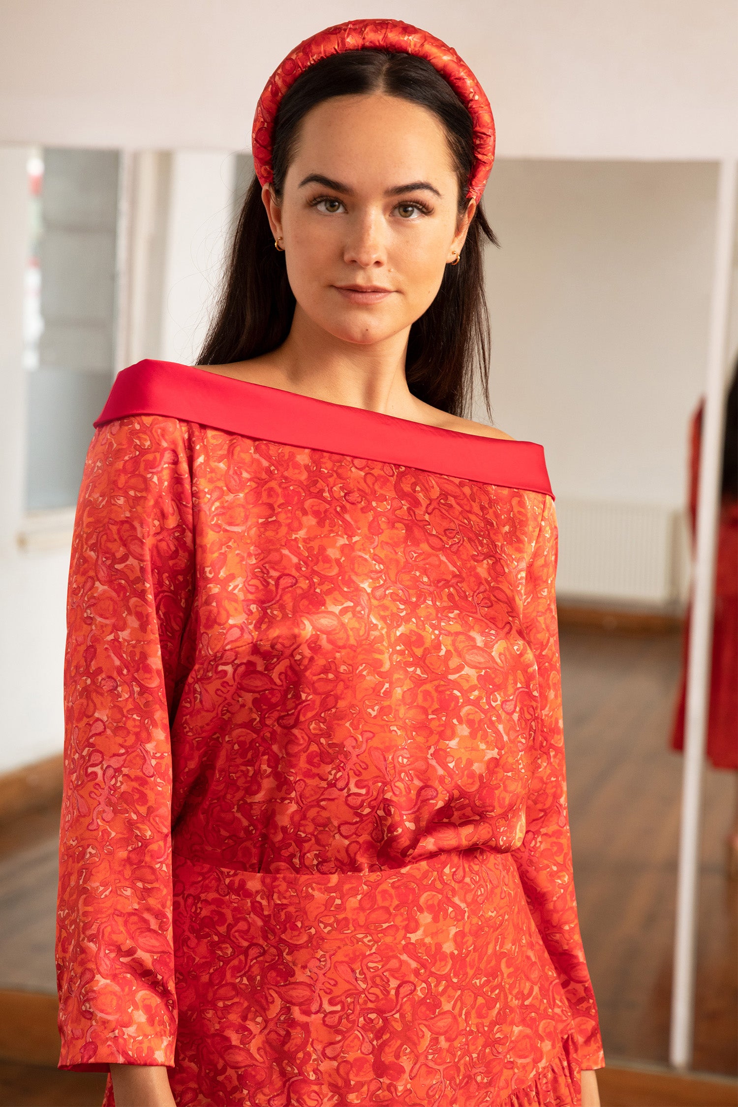 An Isabel Manns reversible boat neckline top with ¾ sleeves in vibrant red print.