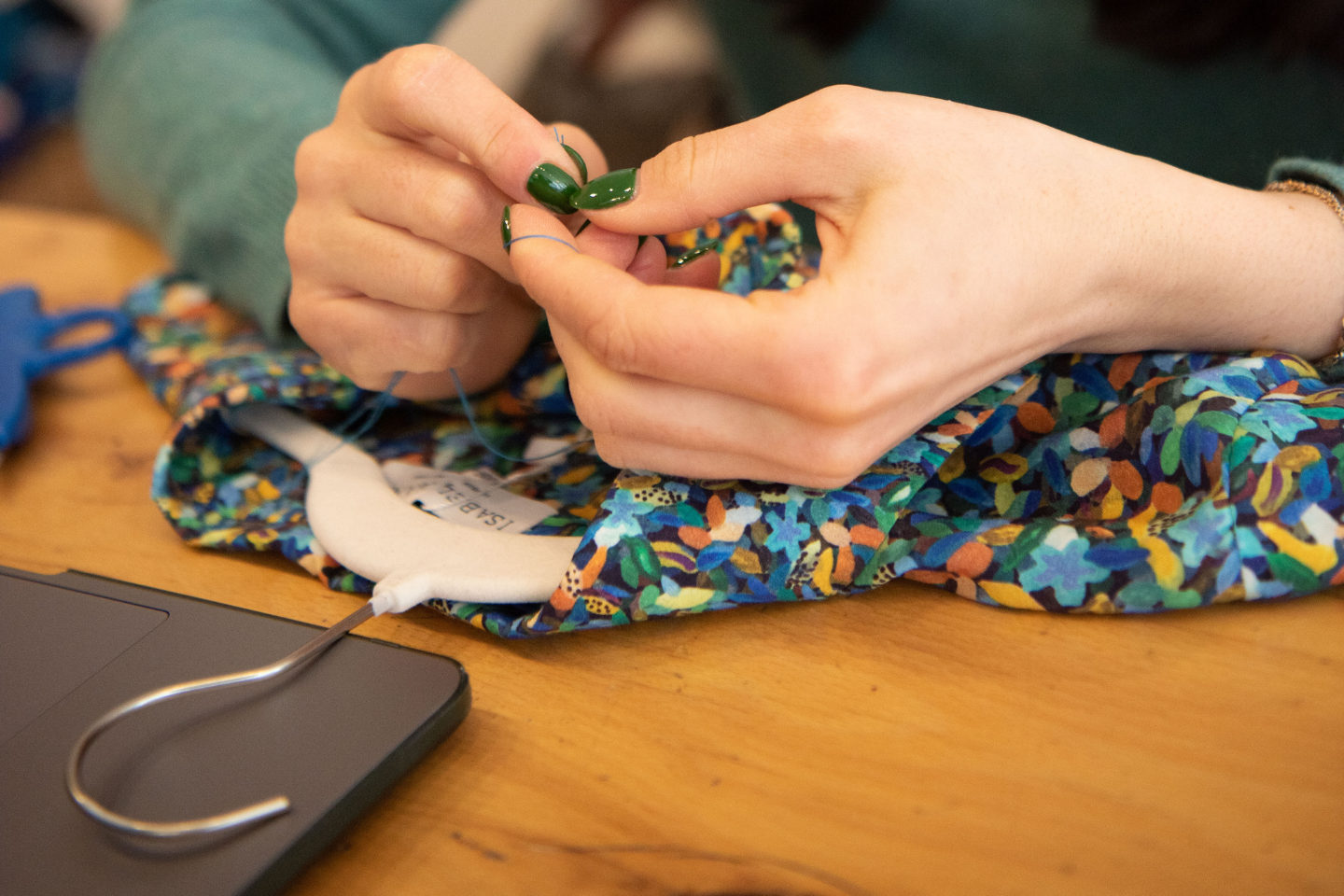 An image of a seamstress hand stitching a label onto an Isabel Manns dress in London