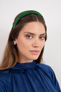 A vibrant emerald green luxurious silk satin headband worn beautifully by a model