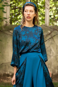 An Isabel Manns long sleeve silk satin top with round neck in teal print.