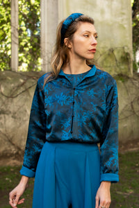 Model wearing reversible box shaped cropped teal printed silk satin jacket, with mandarin collar and black buttons, worn with matching Penelope Trousers and Emily Top.