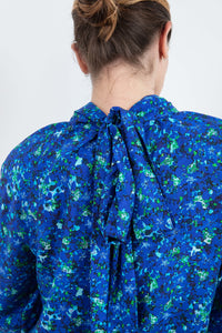 Back of halter neck silk bamboo top with long raglan sleeves with tie collar in blue floral print.