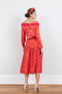 Back view of reversible boat neckline top with ¾ sleeves in vibrant red print, worn with matching Lola Skirt Miami passion and padded headband.