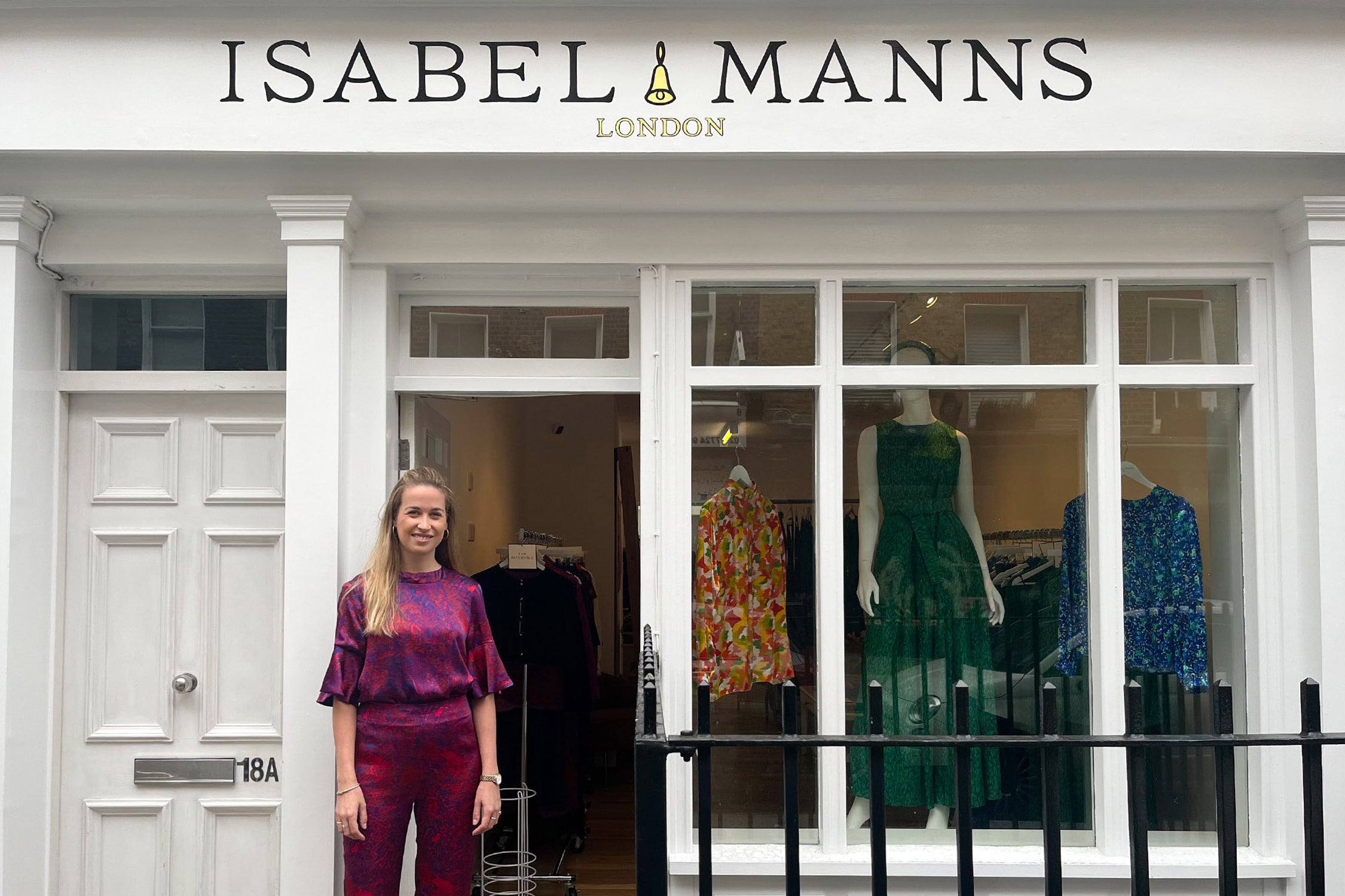 Founder Isabel standing outside the Isabel Manns boutique in Marylebone, London in a red silk satin outfit