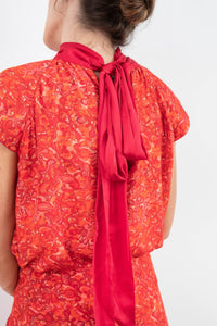 Back view of reversible halter neck silk satin top with tie collar and cap sleeves in vibrant red print.
