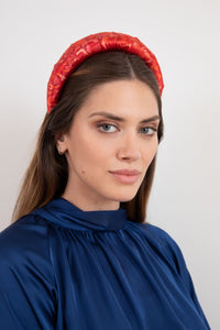 Swirling pattern in pink and red silk satin padded headband elegantly worn by a model