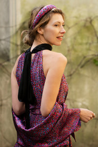 a detail view of a purple dotted printed silk satin halter neck dress back view showing the black collar at the back tied in a bow, and matching scarf