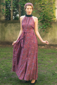 a purple dotted printed silk satin long halter neck style dress with a black collar worn by a model and waist cinched in with a tie belt