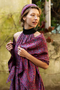 a detail view of a purple dotted printed silk satin halter neck dress showing matching tie belt and black collar, worn with matching scarf