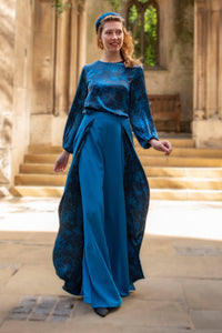 Model wearing an Isabel Manns wide leg wrap around style silk viscose trousers in teal wool crepe and contrasting teal printed silk satin lining, worn with matching silk satin long sleeve top.