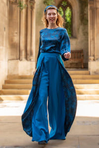 Model wearing an Isabel Manns wide leg wrap around style silk viscose trousers in teal wool crepe and contrasting teal printed silk satin lining, worn with matching long sleeve silk satin top.