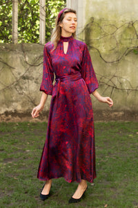 Red marble printed silk satin halter neck dress with keyhole neckline, long elasticated sleeves and a tie belt worn by a model