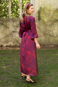 Back view of red marble printed silk satin halter neck dress with keyhole neckline, long elasticated sleeves and a tie belt worn by a model