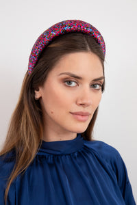 A vibrant dotted purple and pink printed padded headband worn glamorously by a model