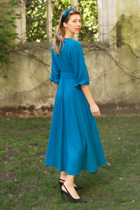 Back view of princess seam wool crepe dress in teal. Features 3/4 length elasticated sleeves, a rounded elegant neckline, and belt with buckle.