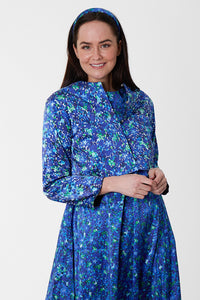 Model wearing reversible box shaped cropped blue floral print jacket, with silver bell fastening, worn with matching A-line Nancy Dress.